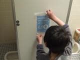 東日本大震災の避難所のトイレにステッカーを貼る男児（写真：NPO法人日本トイレ研究所）