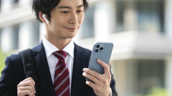 スマートフォンを持つイヤホンをつけたビジネスマン