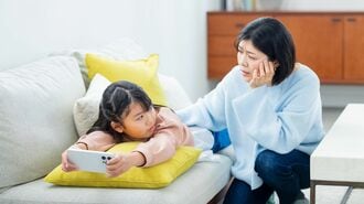 スマホで遊ぶ小学生の女の子と親