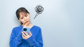 スマホを持って悩む女性