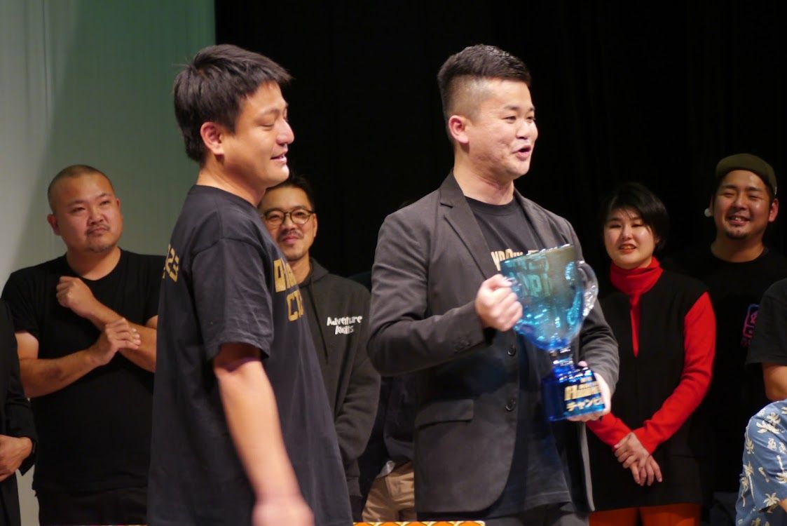 ０−１グランプリ優勝のトロフィー掲げる首里のすけさん（写真：首里のすけ氏さん提供）