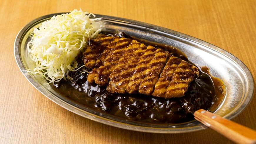 ドロッと濃く、スパイスの香りが立った個性的な味。それゆえ一度食べたら忘れられず、コアなファンを獲得してきた。薄めのロースカツは噛み締めるとソースと肉の旨みが口の中に広がり、ある種ジャンキーなものへの欲を満足させてくれる（撮影：今井康一）