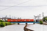 出雲大社前駅に向かって堀川を渡る一畑電車大社線。奥には出雲大社の一の鳥居（撮影：鼠入昌史）