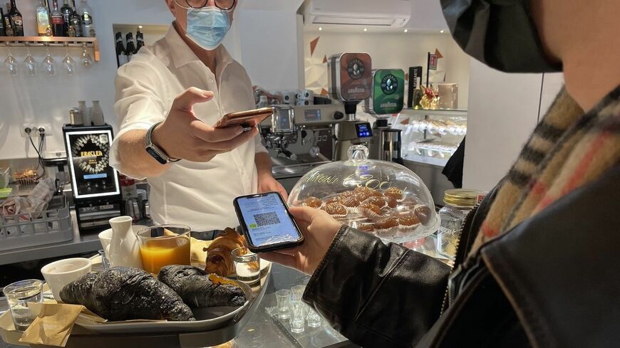 バールでグリーンパスをチェックする店主と客。グリーンパスには顔写真はついていないから、店主にはそのグリーンパスが本当に本人のものかを確認することはできない（筆者撮影）この記事の画像を見る(◯枚)