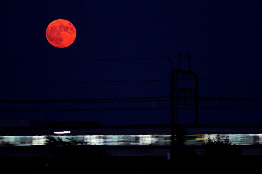 多摩川の上に満月、そして電車＝2015年（撮影：南正時）