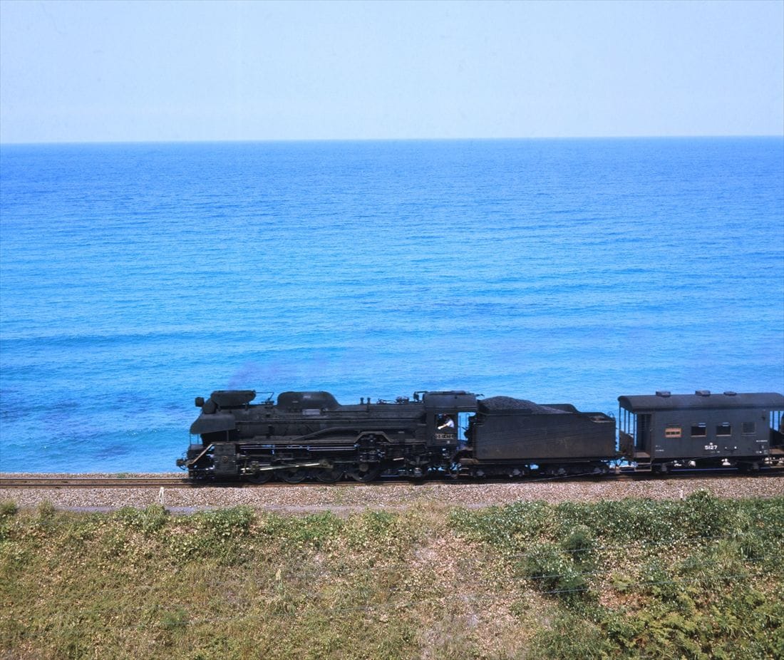 青い日本海をバックに三保三隅付近を走る貨物列車デフレクターと集煙装置に注目（撮影：南正時）