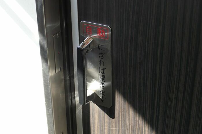 「にぎれば開きます」と書かれた自動ドア。