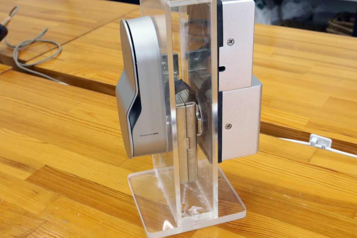 大崎電気工業のスマートロックOPELO。左側が外側の鍵に当たる部分。カバーを開くと暗証番号入力用のテンキーが現れる。右側は内側部分で、鍵の軸を回すモーターと電池ボックスがある（写真：筆者撮影）