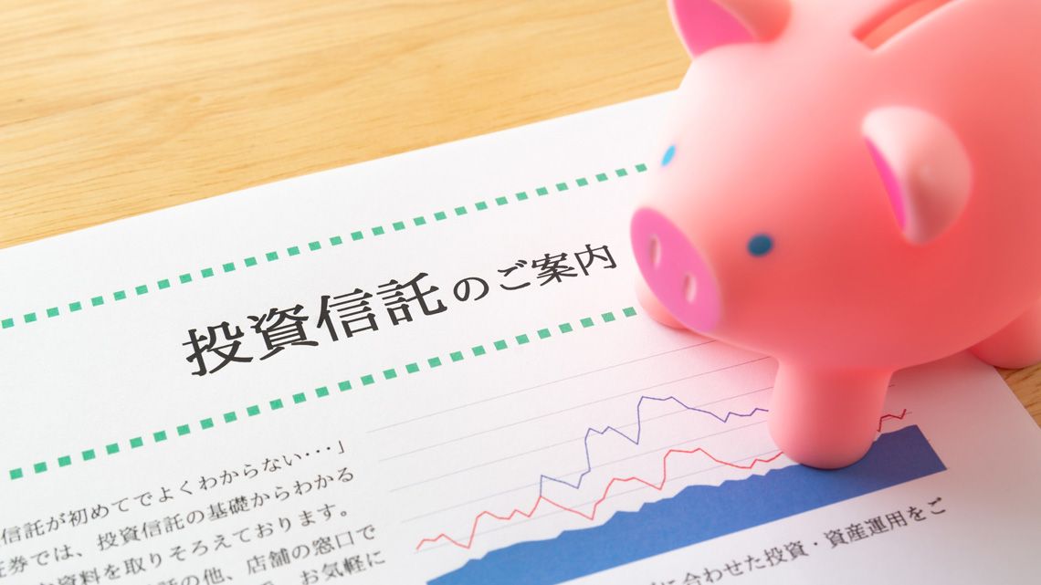 投資信託のパンフレットと豚の貯金箱