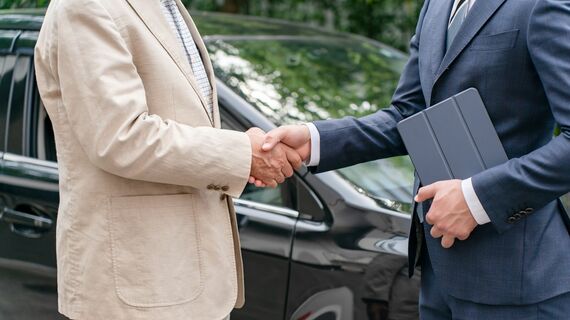 車のディーラーと握手する顧客のイメージ