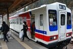 両手に荷物を抱えた乗客が復興支援列車から下車