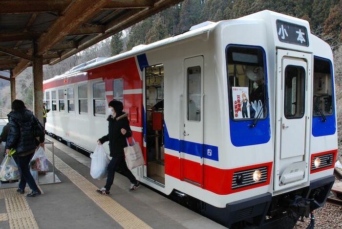 両手に荷物を抱えた乗客が復興支援列車から下車