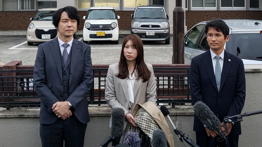 2025年10月21日、富山地方裁判所の外で、弁護士（右）と共に取材に応じる被害者（中央）と夫（左）。日本において被害者が実名を公表して告発し、有罪判決に至るのは極めて稀なケース（写真：AFP＝時事）