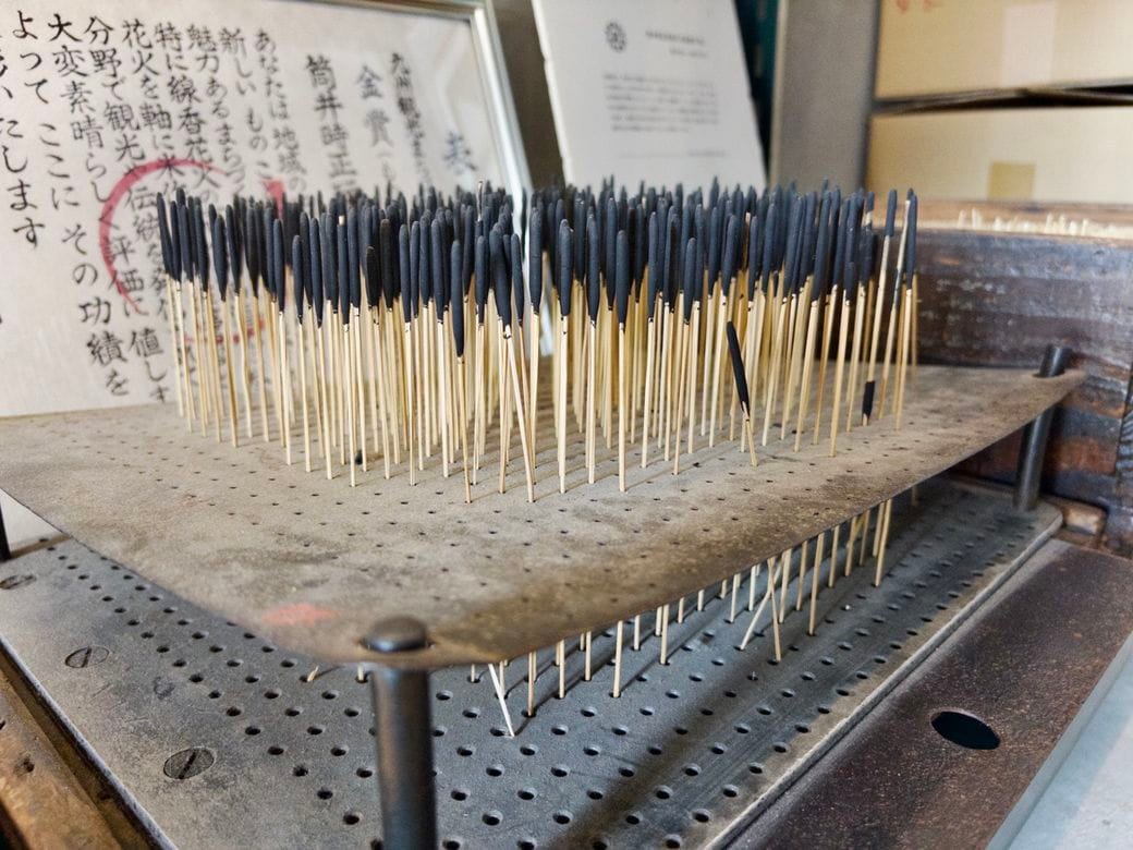 専用の固定器具にセットされた稲藁の芯（スボ）を火薬に浸し、乾かす様子（写真：筆者撮影）