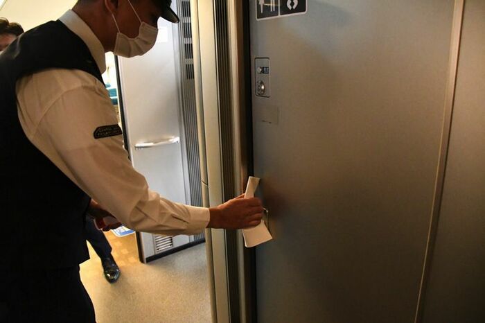 乗務員が巡回中にトイレのドアノブを消毒