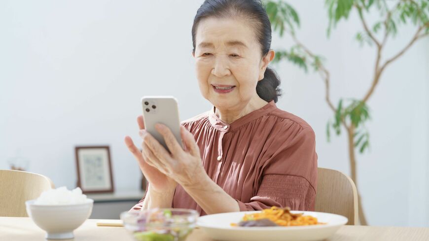 ビデオ通話をしながら食事をするシニア女性