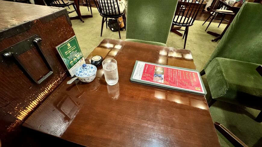 深緑のソファと木製テーブルが並ぶ店内。席間隔は広く、会話のための余白がある（写真：筆者撮影）