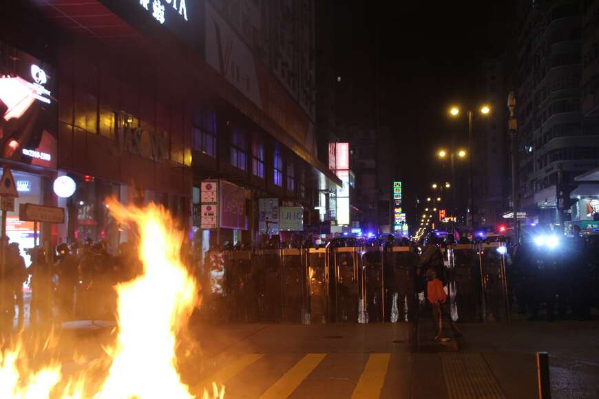 燃えるバリケードと対峙する香港警察の機動隊（写真は2019年9月、記者撮影）