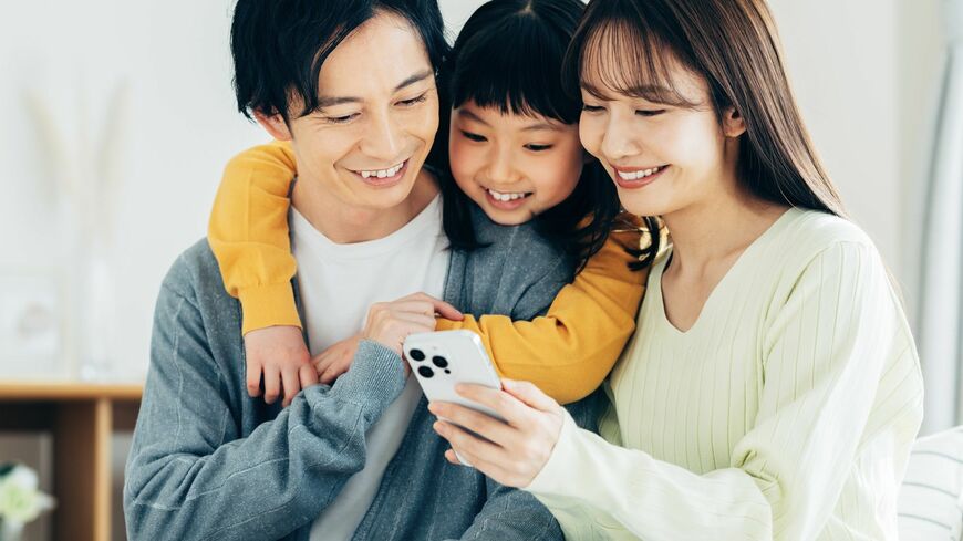 リビングでスマホを見る家族