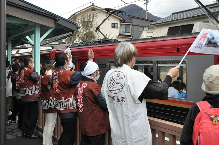 列車に旗や手を振る別所温泉の人々