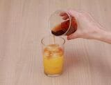 オレンジジュースを入れたコップに、氷を伝わらせながらアイスティーをそっと注ぐ