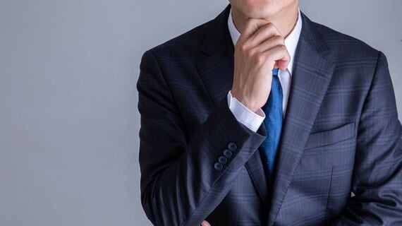 顎に手をあてて思案げなビジネスパーソン