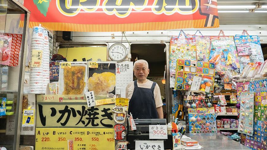 「がもよん」にある「白泉堂」店主の高柳明弘さん。駄菓子屋エリアは明弘さん、喫茶エリアは妻の貴和美さんと、夫婦で役割分担している（筆者撮影）