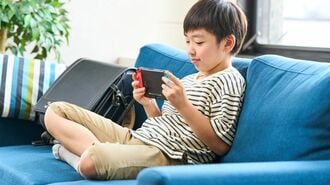 ソファーに座りゲームをする小学生