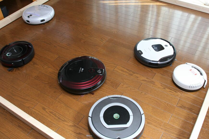 2012年のロボット掃除機。ルンバ780、Hombot（LG）、スマーボV（東芝）、LAQULITO（CCP）、COCOROBO（シャープ）、AIM（ツカモトエイム）。今と形が少し違うし、ゴミ回収充電ドックはなかった（写真：筆者撮影）