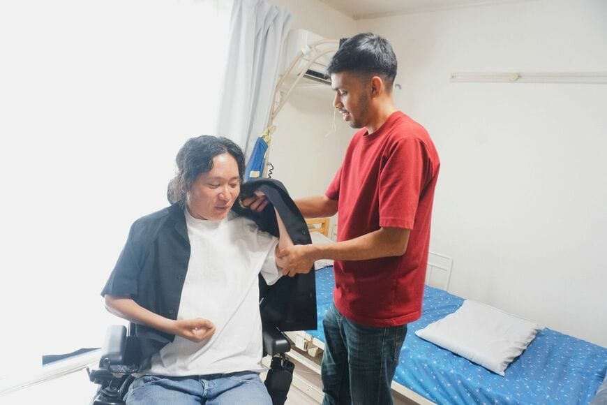 サニーさんに服を着せてもらう近藤さん（写真：筆者撮影）