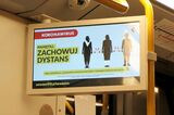ワルシャワ地下鉄車内の情報案内スクリーンに表示される、1.5m以上の距離を保つよう注意喚起する画像（筆者撮影）