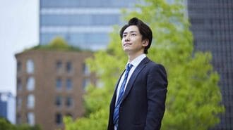 都市のビルを見上げるビジネスパーソン