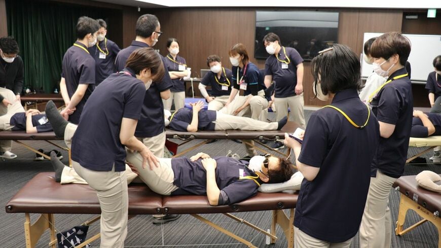 今年の新人研修の様子。講師と生徒が相互にマッサージを行いながら動きを確認していく。後天性で全盲となった女性は「不安も大きかったが、しっかり学んで活躍したい」と抱負を語った（写真：編集部撮影）