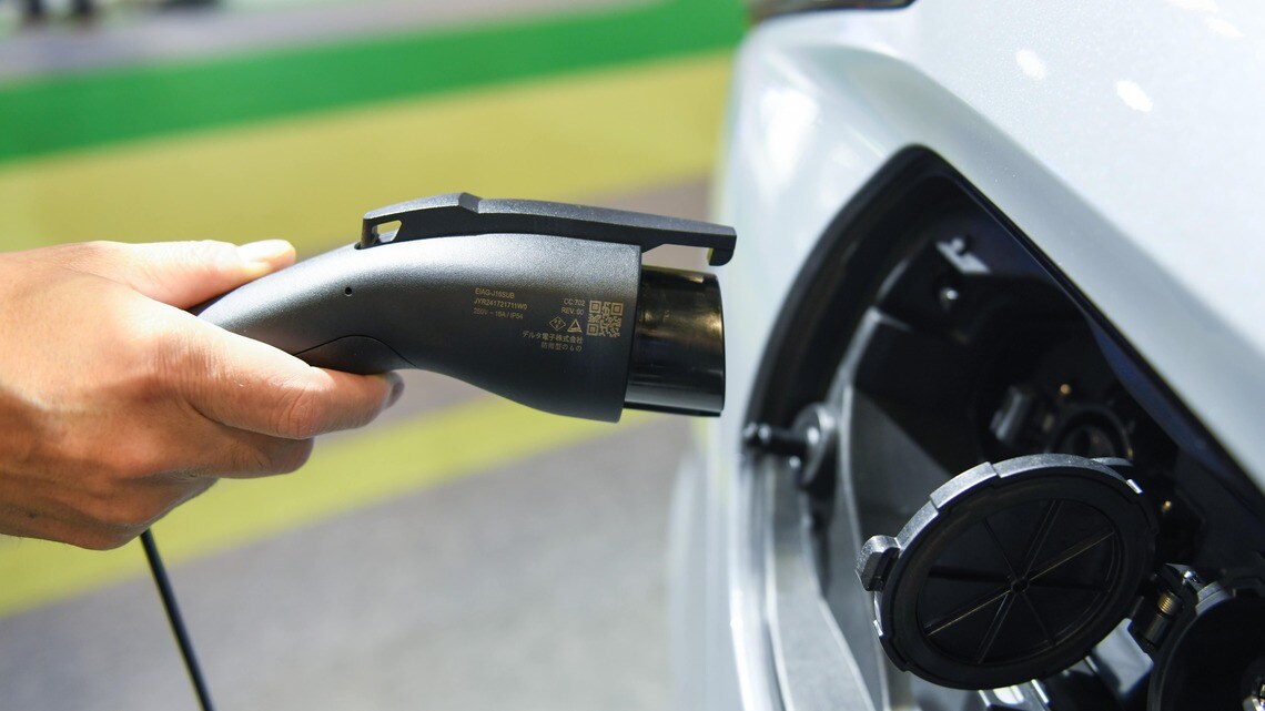 三菱自動車のプラグインハイブリッド車（PHEV）「アウトランダー」の充電を実演する係員。2024年10月15日火曜日、千葉で開催されたジャパンモビリティショーで（写真・2024 Bloomberg Finance LP）