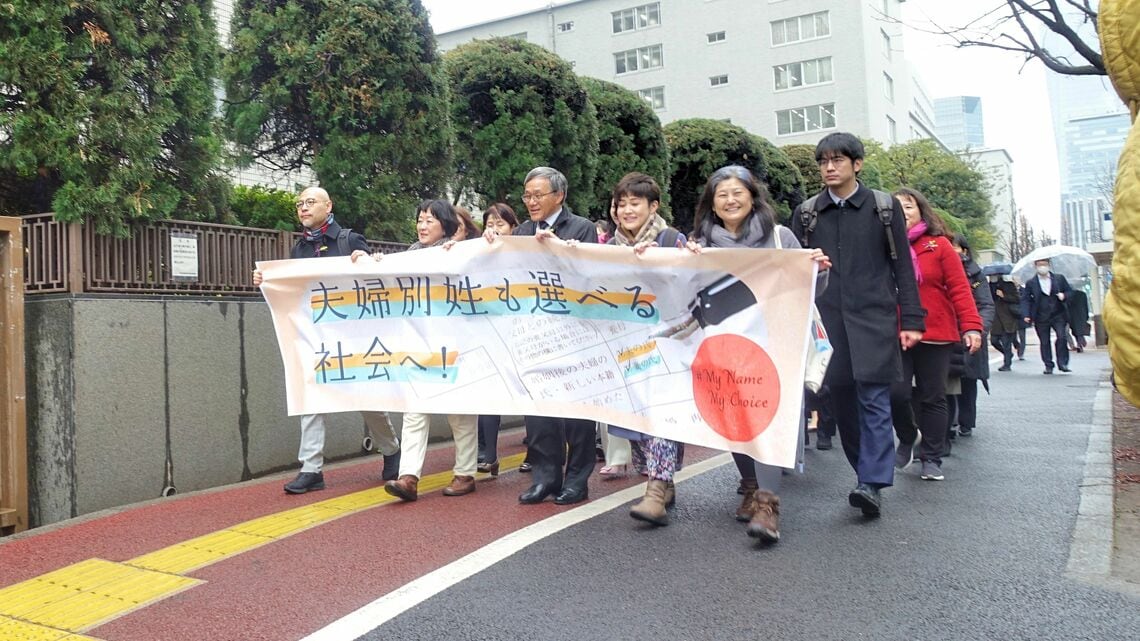 国を提訴した3月8日は国際女性デー。原告団が横断幕を持って東京地裁に入場した（記者撮影）