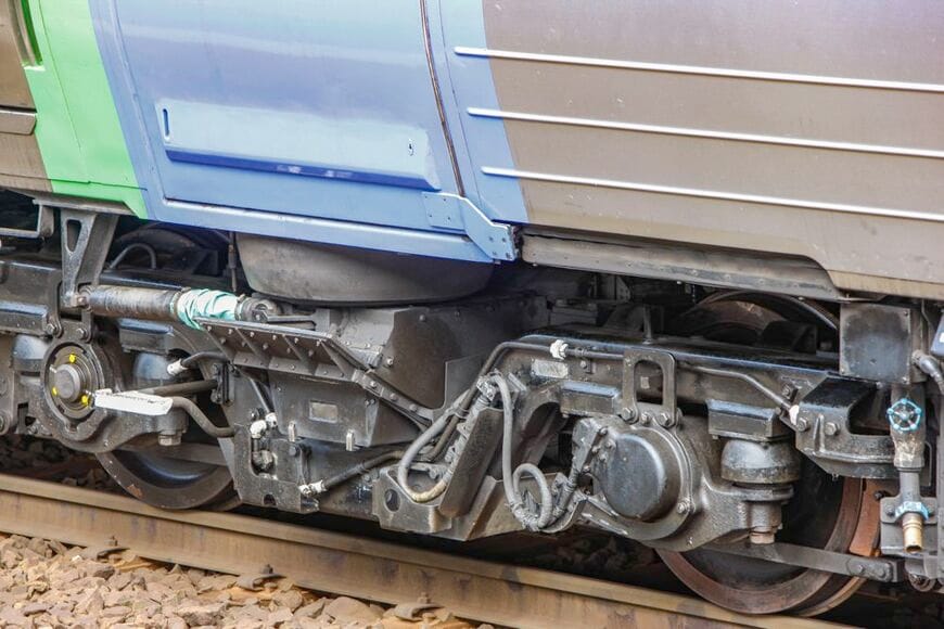 キハ281系のベアリングガイド式振り子台車。パウダースノーの侵入を防ぐため台車枠と振り子梁の間の隙間はふさがれている（筆者撮影）