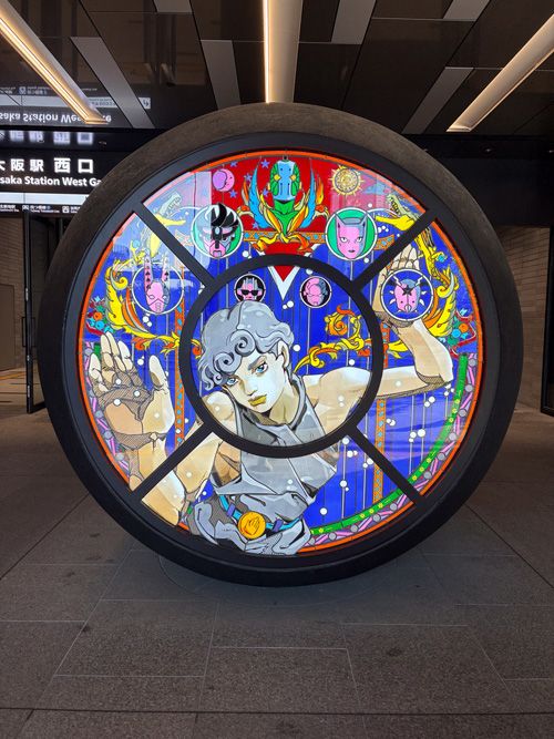 かつてこの場所にあった「噴水小僧」にちなみ、荒木飛呂彦さんが描いたステンドグラスのモニュメント。ノーヴェンバー・レイン、スタープラチナ、キラークイーンも……！ 