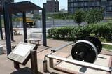 小名木川貨物駅跡の一角に整備された公園には、ここがかつて貨物駅だったことを解説する案内板と鉄道車両の車輪が設置されている（筆者撮影）