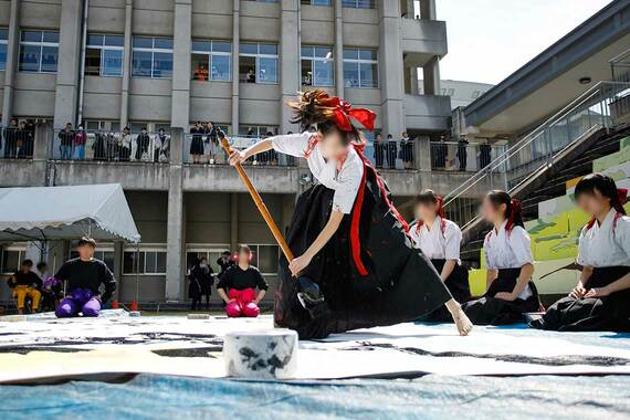 女子生徒が大きな筆で字を書く様子