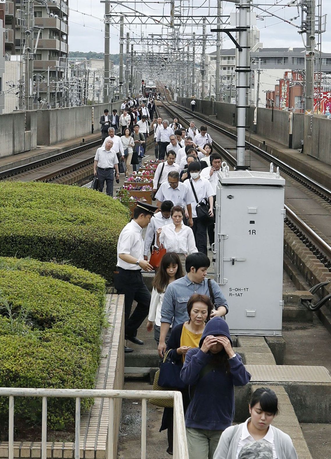 運行中止となった列車から降りて線路上を歩く人々