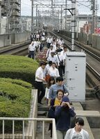 運行中止となった列車から降りて線路上を歩く人々