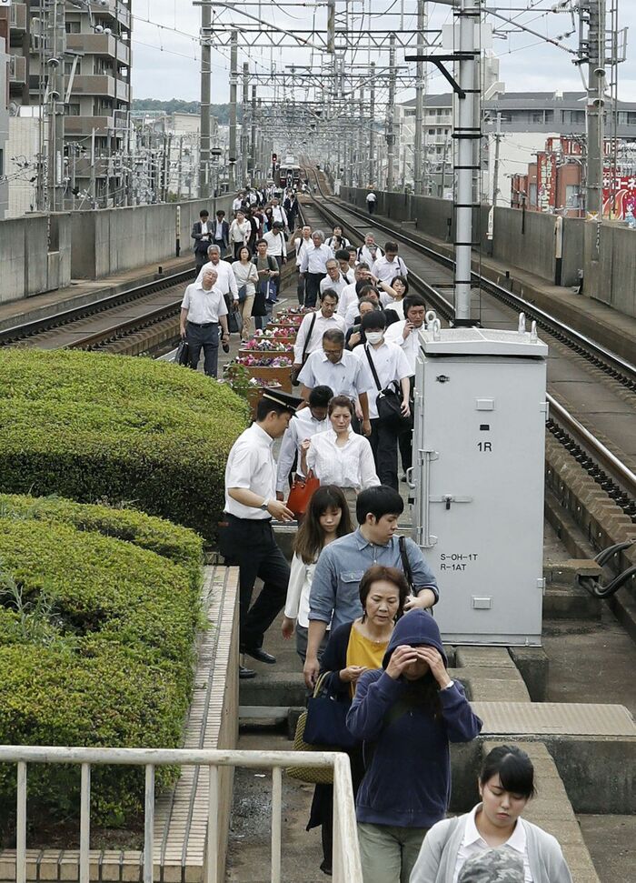 運行中止となった列車から降りて線路上を歩く人々