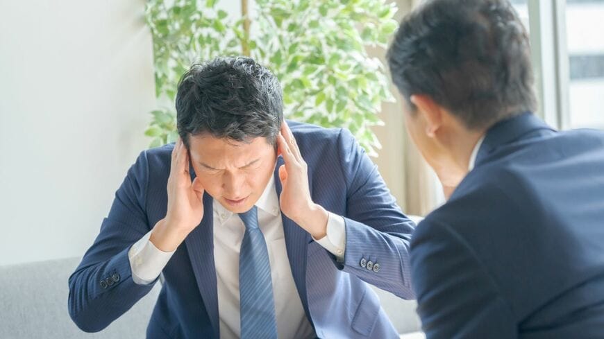 耳をふさぐビジネスマン