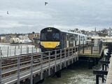 イギリス・ワイト島を走る「桟橋鉄道」アイランドラインの電車。陸地側の駅を出発して桟橋にさしかかったところ。奥にホーバークラフトの姿も見える（筆者撮影）