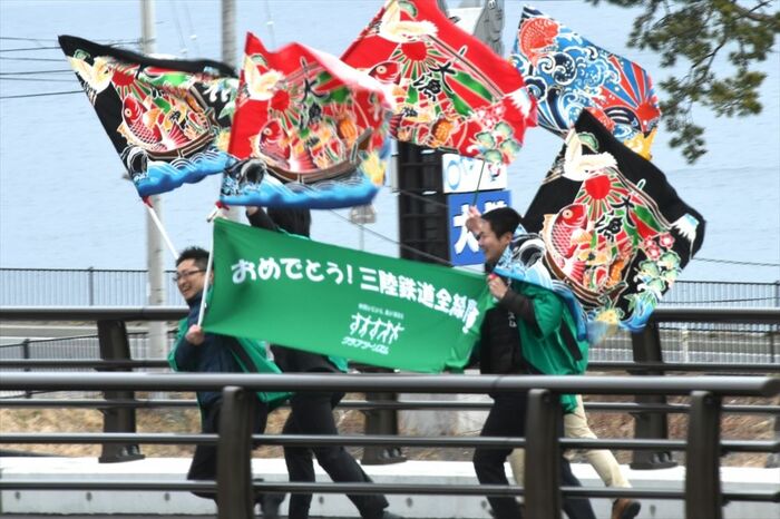 大漁旗を振って記念列車を歓迎する沿線の人々