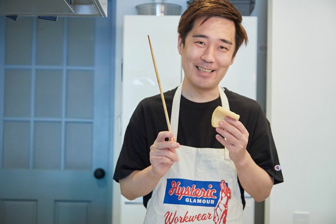 菜箸と油揚げを手に微笑む野本やすゆきさん（写真：吉澤健太）