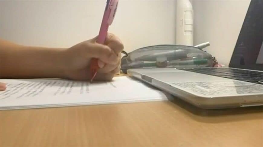 パソコンを見ながら資料に書き込む、勉強中の様子