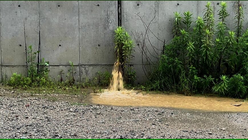 あふれた水を貯める調整池から濁水が勢いよく漏れだしていた（写真：須藤啓二さん撮影の動画から）