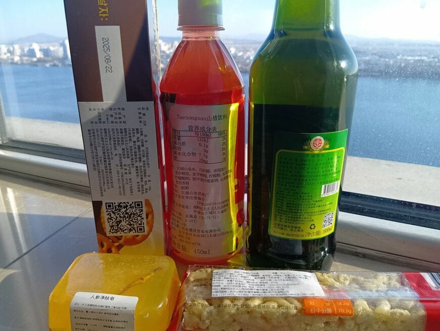 購入した商品。なお奥に見える街はすべて北朝鮮。ちなみに黄色の商品は石鹸で、北朝鮮に船で近づいた話を含め、詳細は別記事にまとめた（写真：筆者撮影）