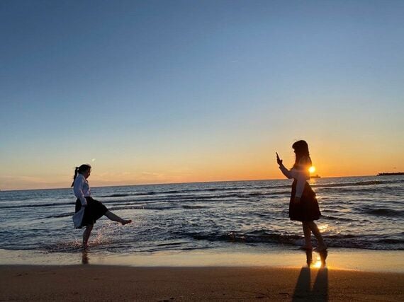 夕暮れ時の海で女子2人が遊んでいる様子